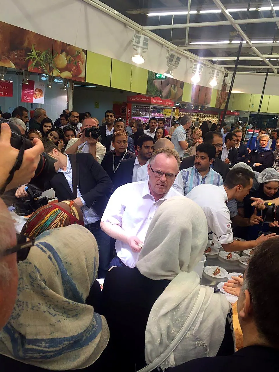 A chef and guests at a busy in-store seafood demonstration