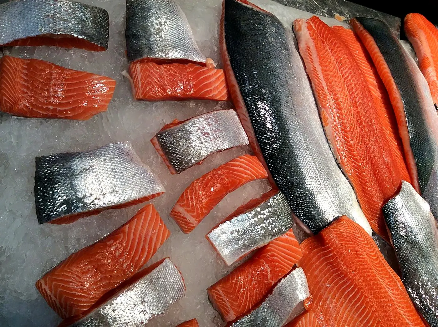 Salmon portions and whole fillets, skin-on, on crushed ice